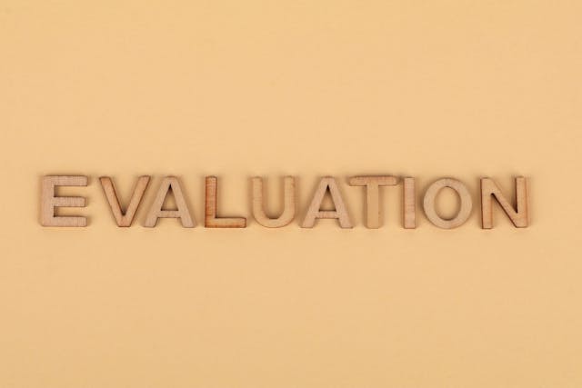 The word “Evaluation” from wooden letters against a brown background.