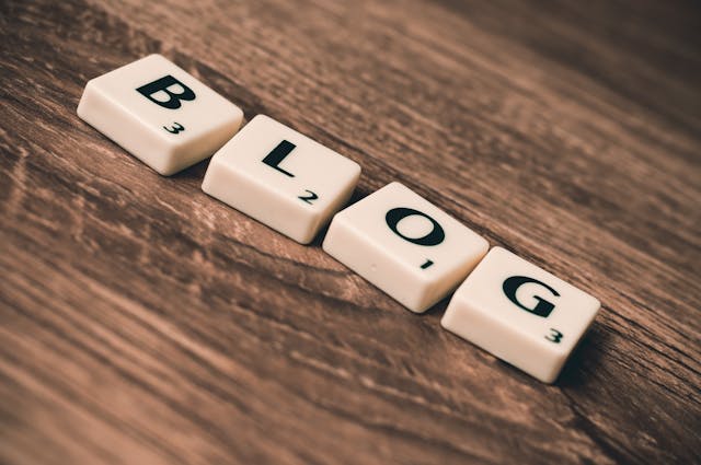 White tiles arranged to spell the word ‘blog’ on a rustic wooden surface.