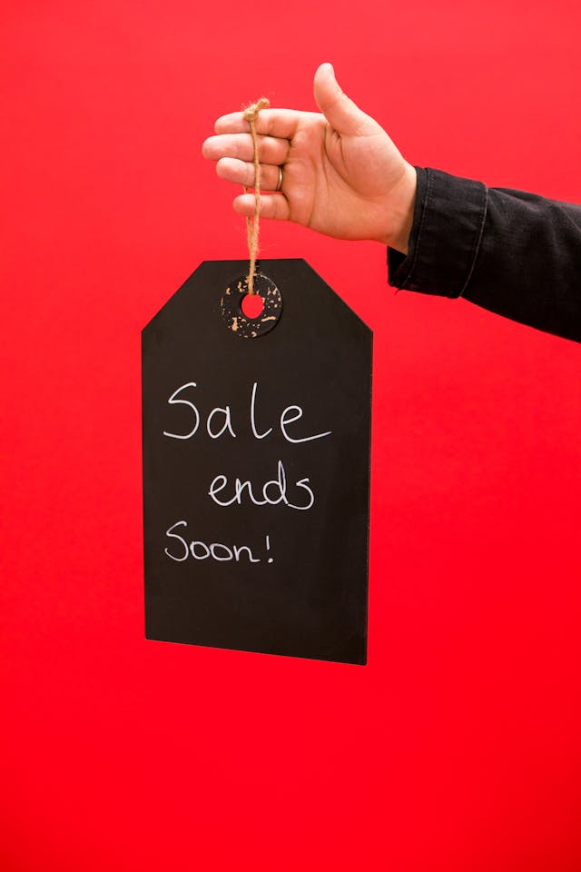 A hand holding a large black price tag with the words "Sale ends Soon!" written in white.