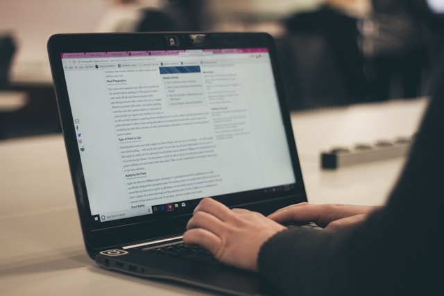 A person typing on a laptop, working on a blog post in a quiet setting.