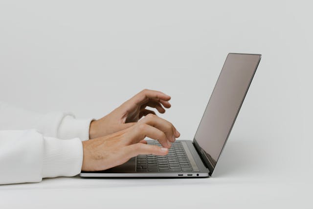 Close-up of hands typing on a laptop.