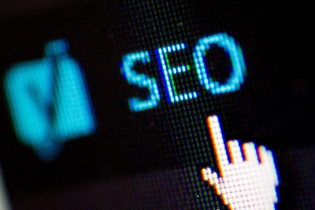 A close-up of a digital screen showing the word "SEO" with a hand cursor icon, representing search engine optimization.