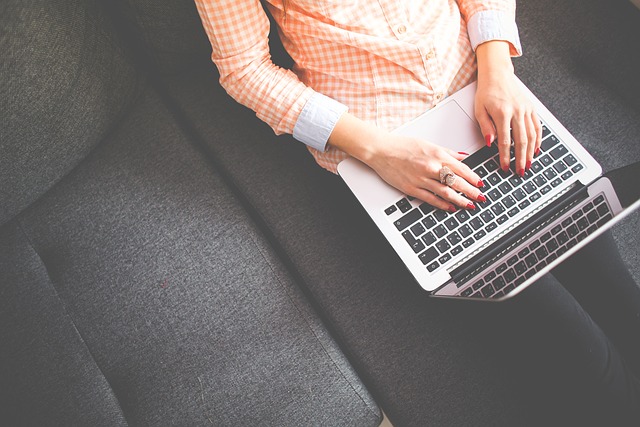 A person typing on a laptop while sitting on a couch, representing blog writing, content creation, and digital storytelling.