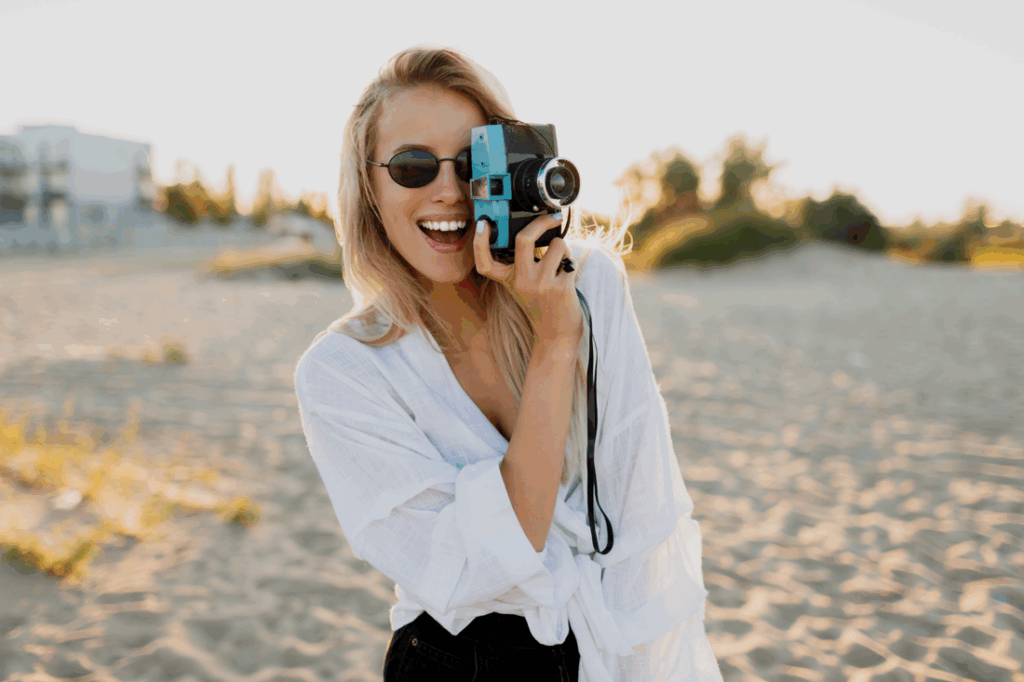 A young female travel blogger holding a camera while filming her trip.